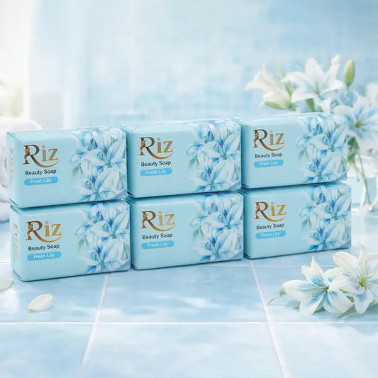 Six bars of Riz Fresh Lily beauty soap for natural glow placed on a blue tiled surface with white lilies.